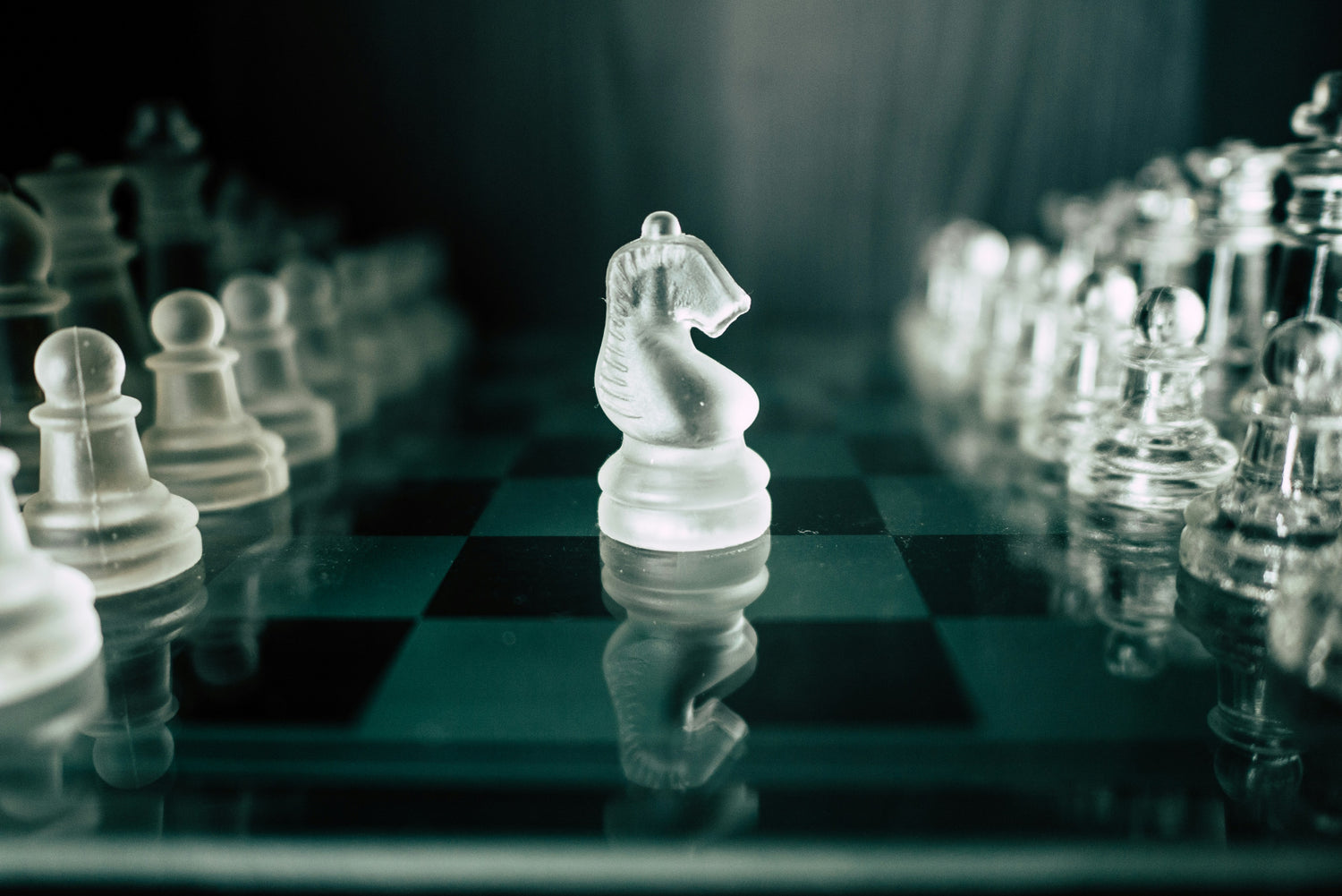 Clear glass chess pieces on a chessboard with a dark background
