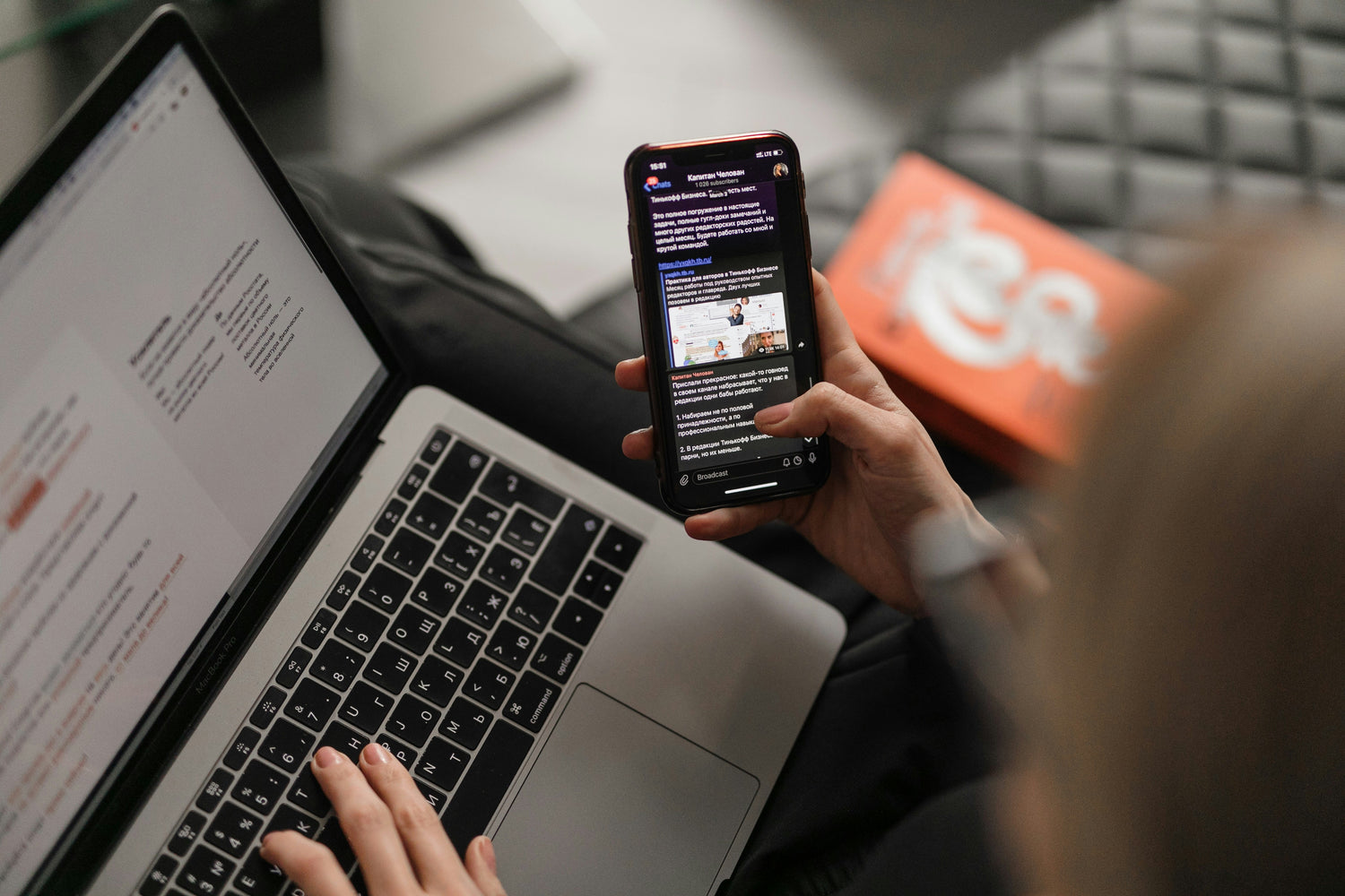 Person using a laptop and smartphone with a blurred in the background